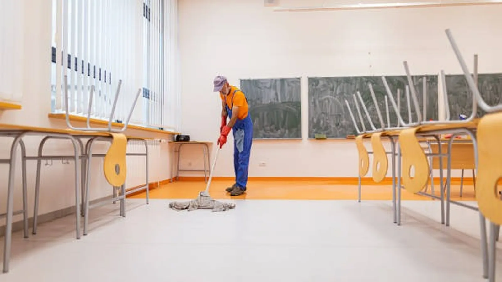 Boş bir sınıfta yer temizliği yapan görevli